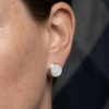 Boucle d'oreille puce en argent et nacre blanche ronde, portée sur l'oreille.