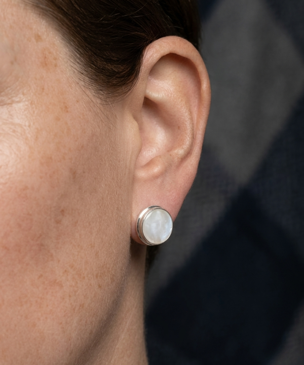 Boucle d'oreille puce en argent et nacre blanche ronde, portée sur l'oreille.