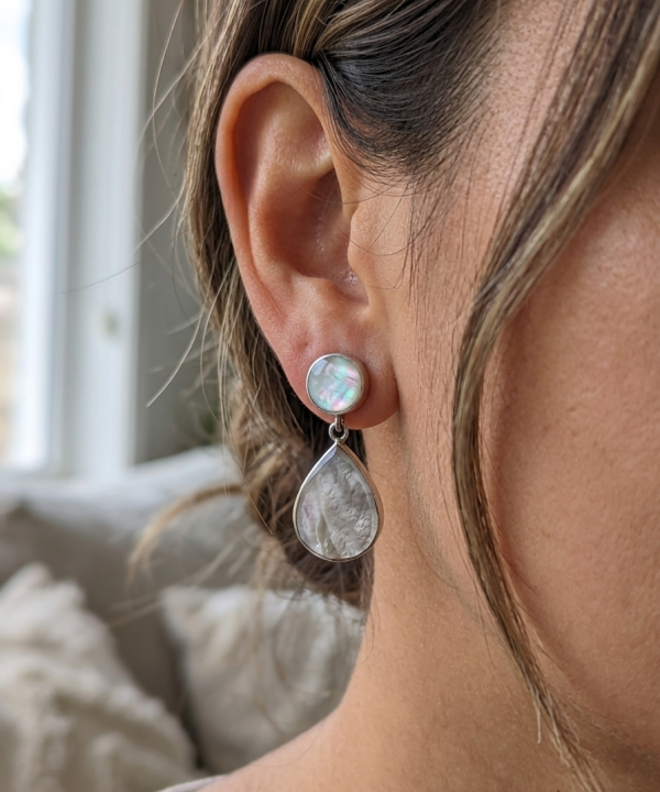 Boucle d'oreille pendante en argent et nacre blanche portée à l'oreille.