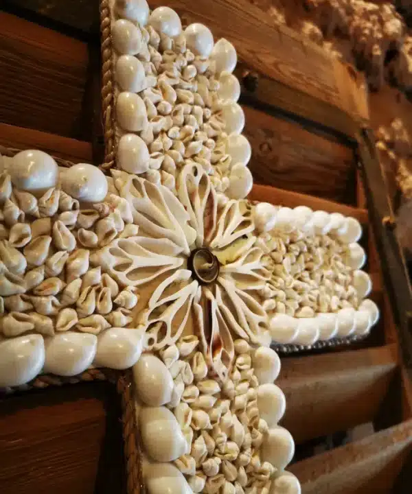 Croix artisanale balinaise en coquillages naturels blancs et crème, motif rosace central.