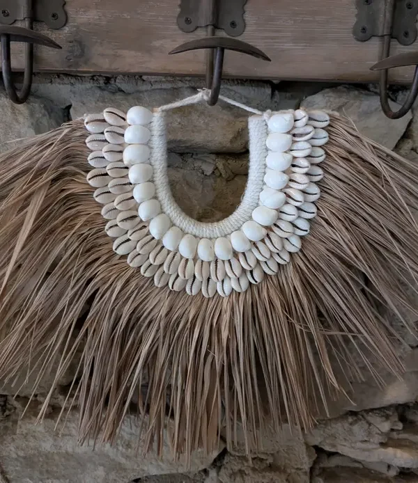 Décoration murale demi-lune artisanale en paille, coquillages cauris et laine, style bohème de Bali.