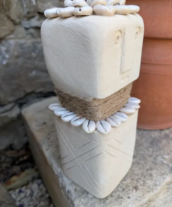 Statuette Sumba artisanale en grès crème, cauris blancs et jute, symbole de protection.