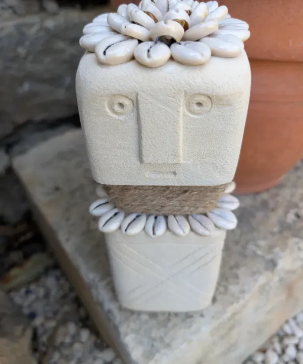 Statuette Sumba artisanale en grès crème, cauris blancs et jute, symbole de protection.