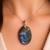 Pendentif labradorite artisanal poli, forme ovale allongée, reflets irisés bleus et or.