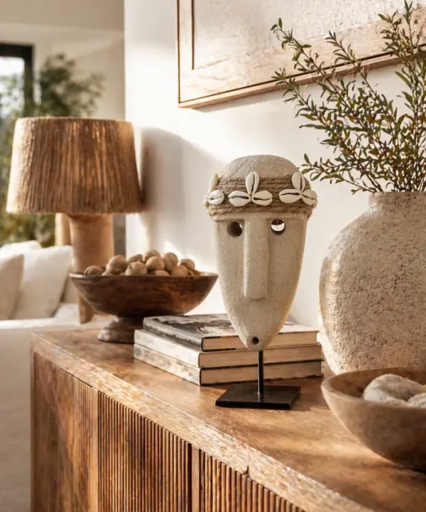 Statuette Sumba artisanale en grès beige, visage tribal avec bandeau cauris sur socle.