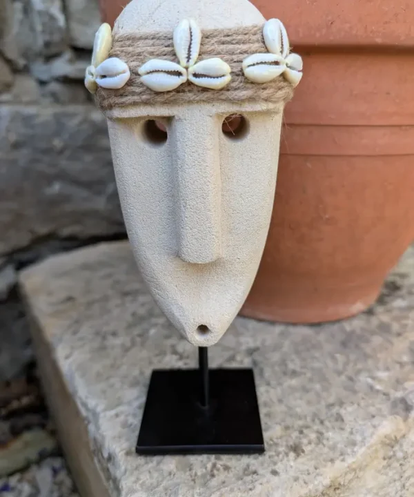 Statuette Sumba artisanale en grès beige, visage tribal avec bandeau cauris sur socle.