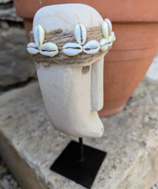 Statuette Sumba artisanale en grès beige, visage tribal avec bandeau cauris sur socle.