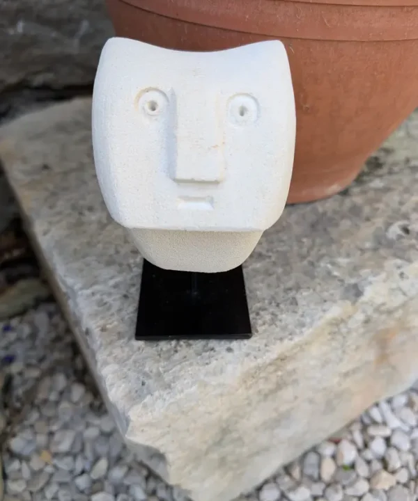 Statuette artisanale Sumba en grès beige, visage abstrait géométrique sur socle noir.