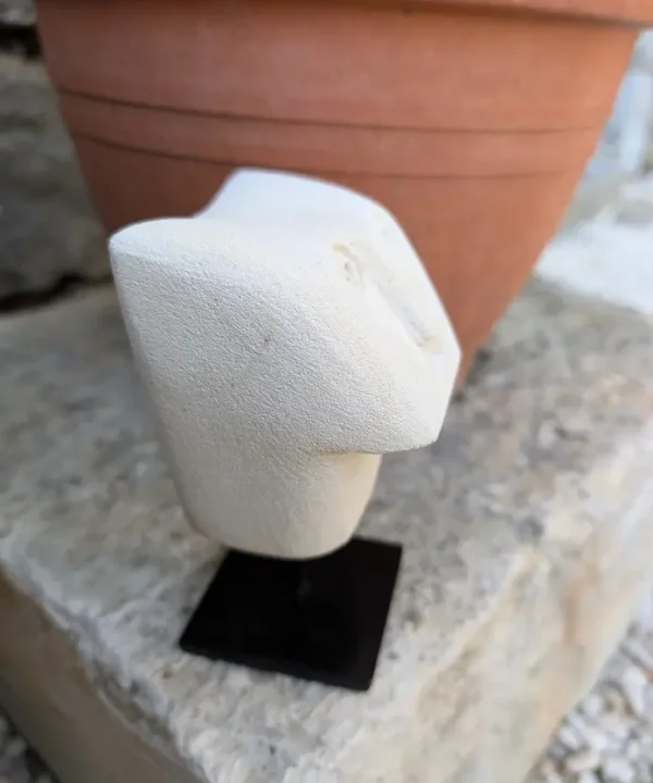 Statuette artisanale Sumba en grès beige, visage abstrait géométrique sur socle noir.